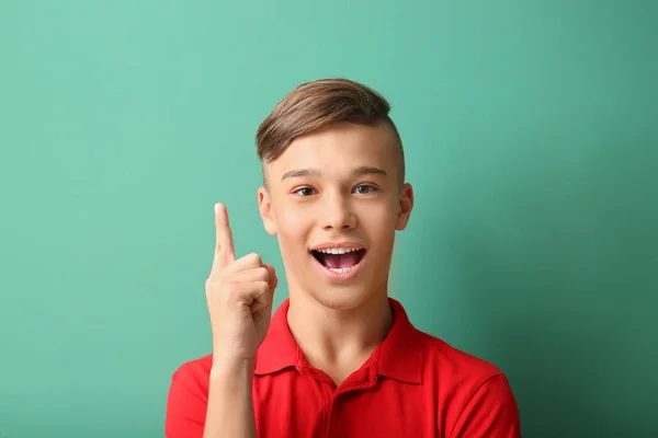 Teenage boy with raised index finger on color background — Stock Photo, Image