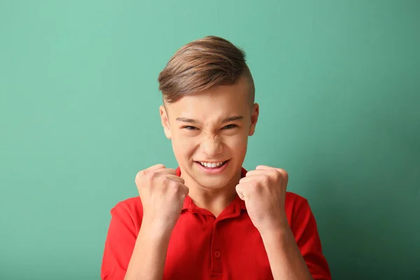 Emotional teenage boy with clenched fists on color background — Stock Photo, Image