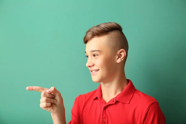 Adolescente chico apuntando a algo en el fondo de color — Foto de Stock