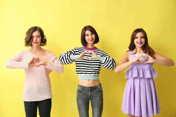 Portrait of beautiful women making hearts with their hands on color background — Stock Photo, Image