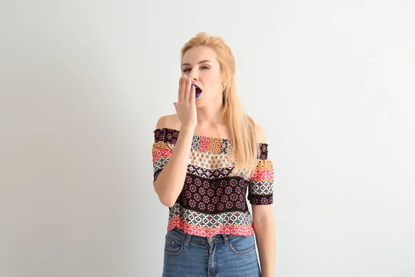 Portrait of beautiful yawning woman with unusual lipstick on white background