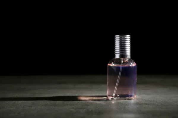 Бутылка духов на сером столе — стоковое фото