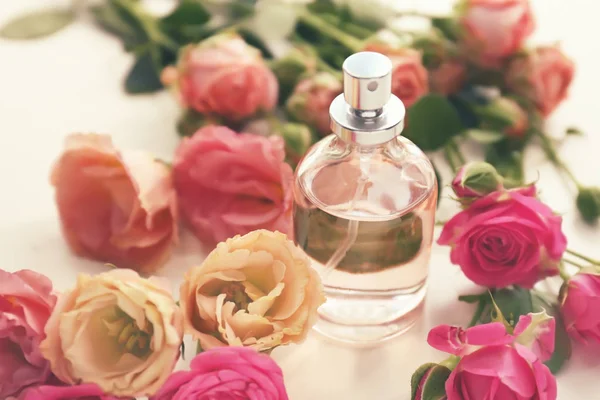 Garrafa de perfume com belas flores na mesa branca — Fotografia de Stock