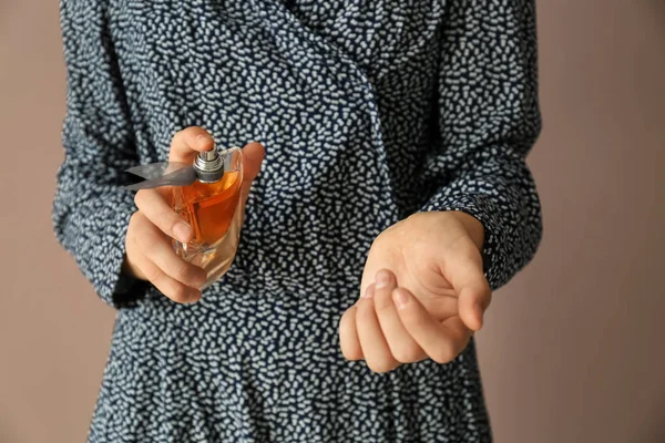 Woman with bottle of perfume on color background, closeup — Stock Photo, Image