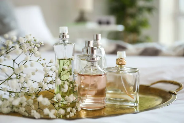 Metalltablett mit Parfümflaschen und Blumen auf dem Bett — Stockfoto