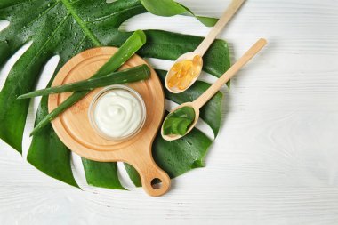 Krem, aloe vera ve Beyaz ahşap masa haplarla kase