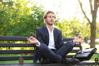 Yakışıklı genç işadamı parkta bankta meditasyon