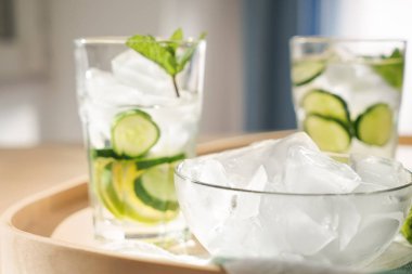 Buz küpleri ve bardak taze salatalık su tepsi ile kase