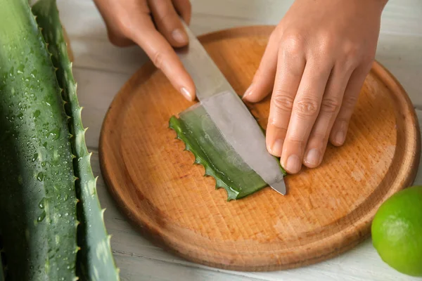 Woman cutting aloe vera leaf on wooden board, closeup — Stock Photo, Image