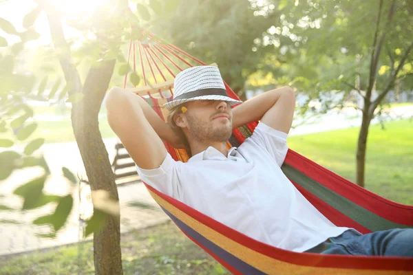 Bonito jovem descansando na rede ao ar livre — Fotografia de Stock