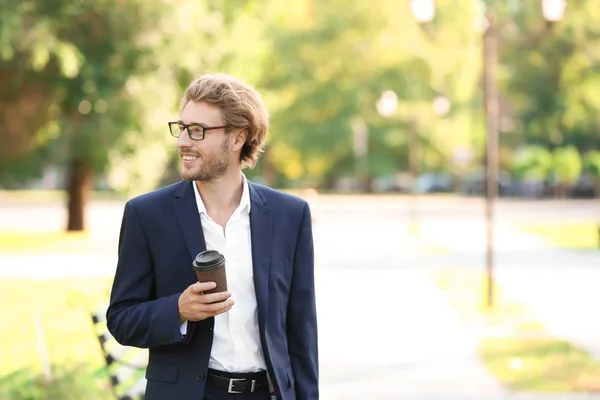 Handsome young businessman with coffee resting in park — Stock Photo, Image