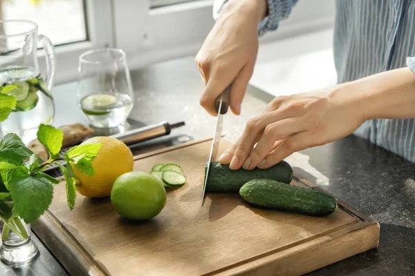 Vrouw snijdt verse komkommer aan tafel — Stockfoto