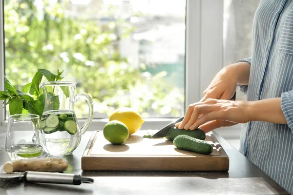 Frau schneidet am Tisch frische Gurken — Stockfoto