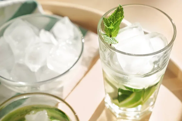 Glass of fresh cucumber water with ice cubes on tray, closeup — Stock Photo, Image