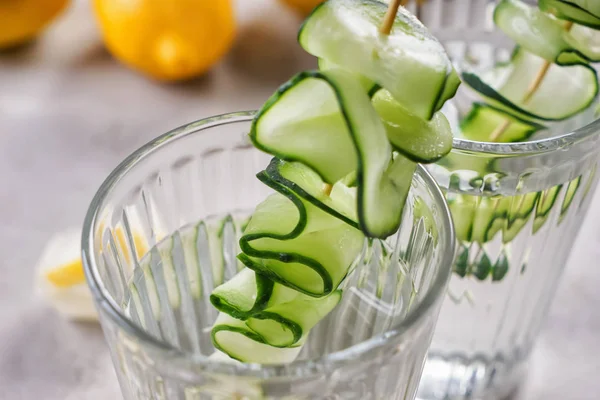 Glasses of fresh cucumber water on table, closeup