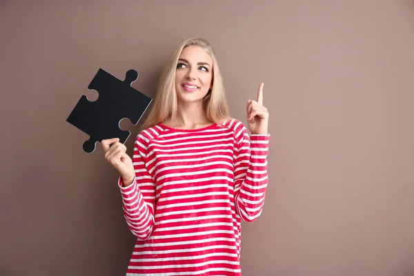 Jonge vrouw met stuk puzzel en getogen wijsvinger op kleur achtergrond — Stockfoto