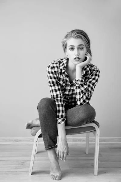 Black and white portrait of beautiful young woman sitting on stool — Stock Photo, Image