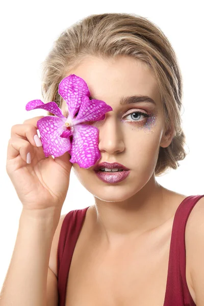 Mujer joven con hermoso maquillaje y flor sobre fondo blanco — Foto de Stock