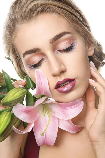 Mujer joven con hermoso maquillaje y flor sobre fondo blanco — Foto de Stock