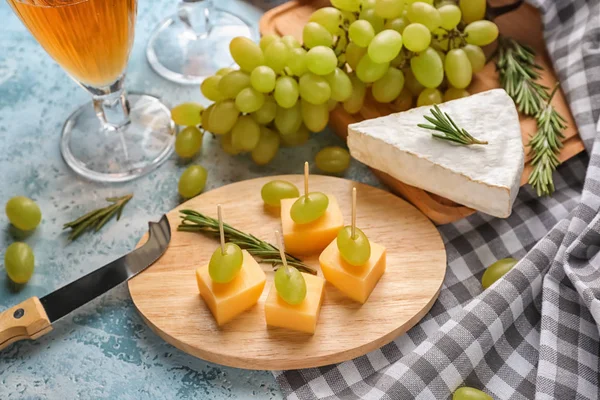 Tablero de madera con deliciosos canapés en mesa de color —  Fotos de Stock