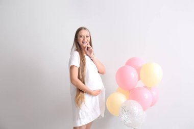Beyaz arka planda balonları olan güzel hamile bir kadın.