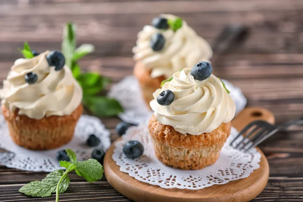 Delicious cupcakes with blueberries on wooden table — Stock Photo, Image