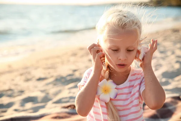 Cute little girl with sea shell on beach — Stock Photo, Image