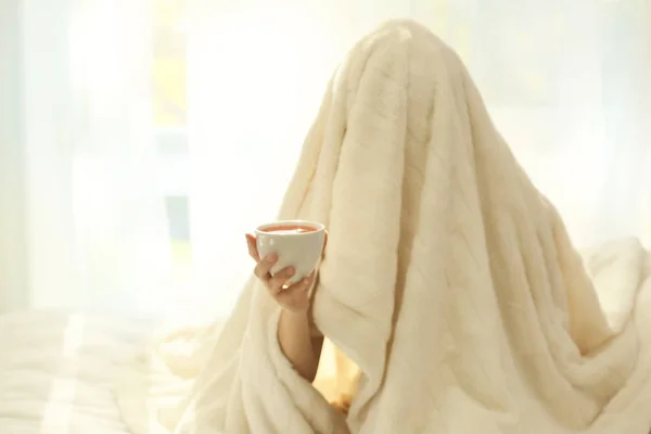 Uykulu kadın yatakta kahve ile battaniyenin altında — Stok fotoğraf