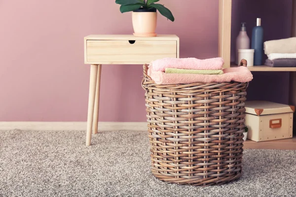 Wicker basket with folded clean towels on floor in bathroom — Stock Photo, Image
