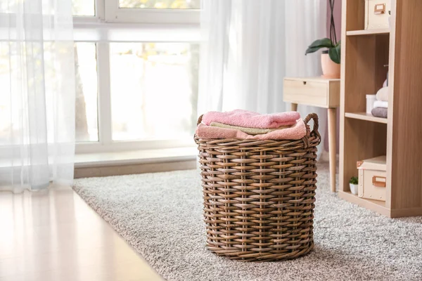 Плетеная корзина с сложенными чистыми полотенцами на полу — стоковое фото