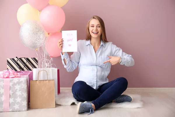 Beautiful pregnant woman with baby shower gifts near color wall — Stockfoto