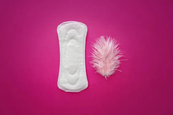 Almohadilla menstrual con plumas sobre fondo de color —  Fotos de Stock