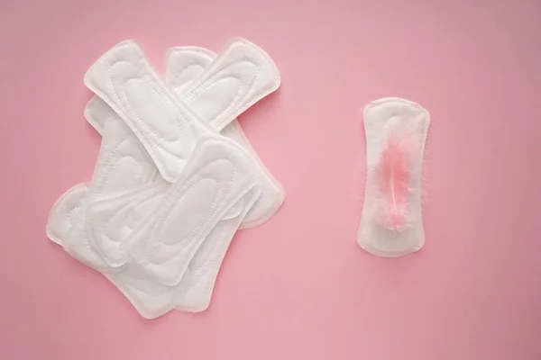 Menstrual pads with feather on color background — Stock Photo, Image