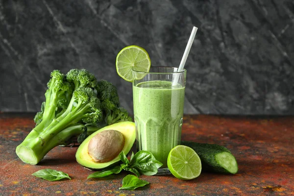 Copo de smoothie verde saboroso e ingredientes na tabela de cores — Fotografia de Stock