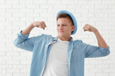 Kasları beyaz duvara karşı gösterilen yakışıklı genç adam portresi