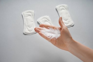 Tüy ve gri arka plan üzerinde adet yastıkları kadın ile