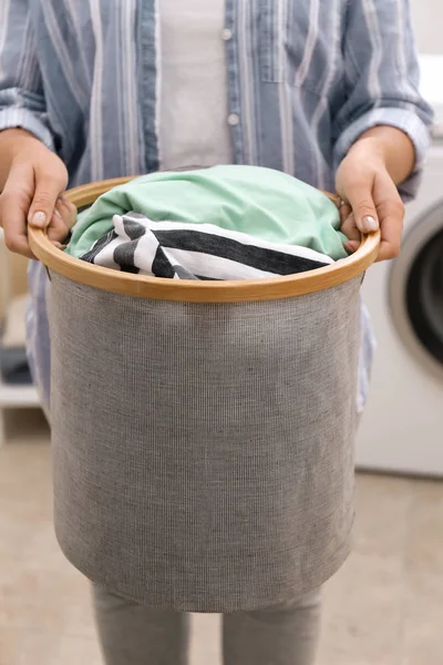 Женщина держит корзину для белья с грязной одеждой в ванной — стоковое фото