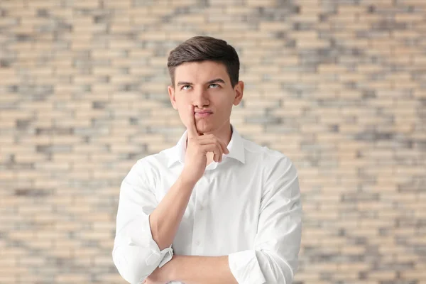 Portrait of handsome thoughtful young man against brick wall — Stock Photo, Image