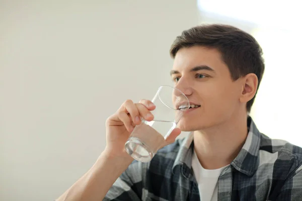 Young man drinking water at home — Stock Photo, Image