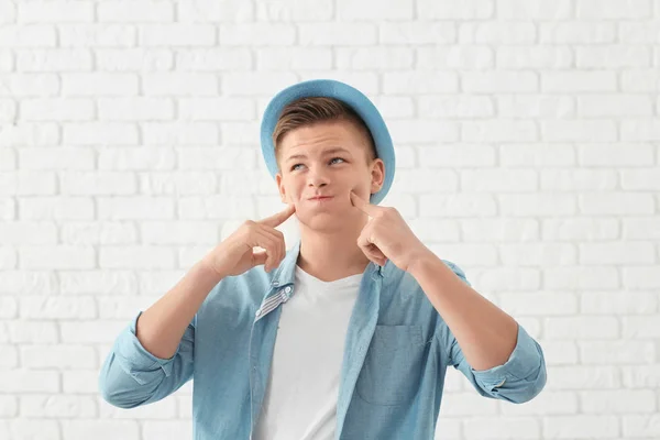 Retrato engraçado de jovem bonito contra parede de tijolo branco — Fotografia de Stock