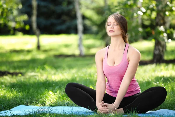 Mujer joven practicando yoga al aire libre — Foto de Stock