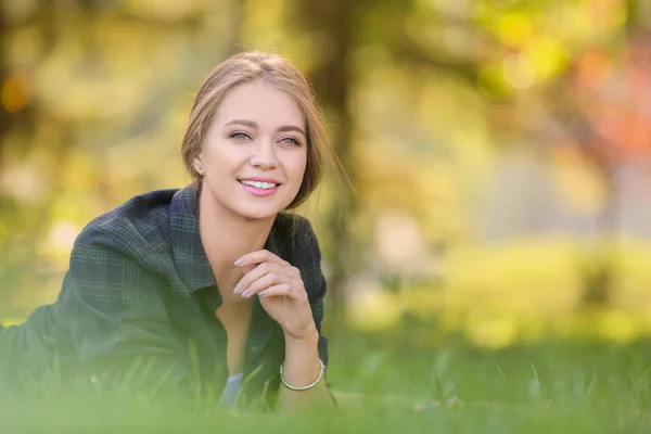 Belle jeune femme couchée sur l'herbe verte à l'extérieur — Photo