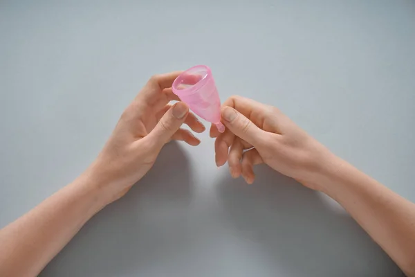 Femeia care deține ceașcă menstruală pe fundal gri — Fotografie, imagine de stoc