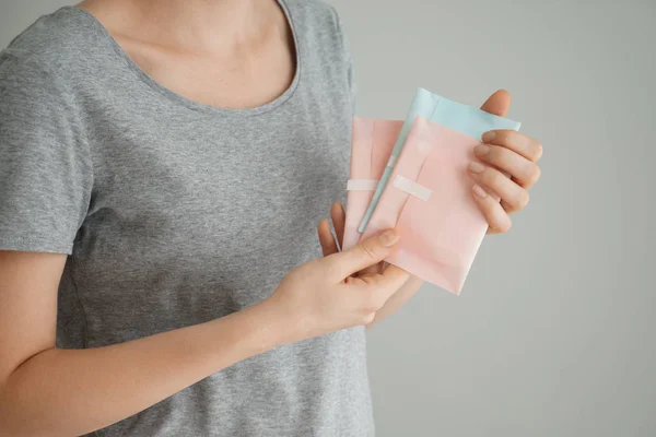 Woman holding menstrual pads on grey background — Stock Photo, Image