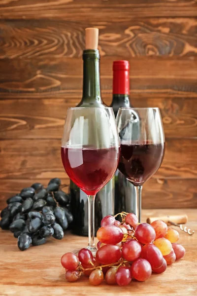 Bicchieri di vino e uva fresca sul tavolo di legno — Foto Stock