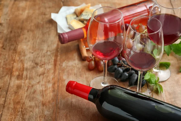 Стаканы и бутылки с вином на деревянном столе — стоковое фото