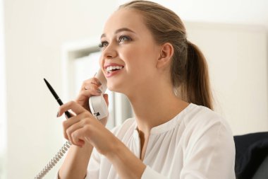 Güzel kadın Sekreter ofiste telefonda konuşuyor