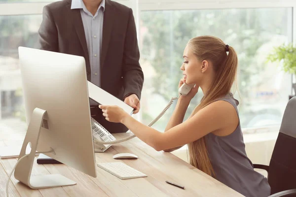 Beautiful female secretary working with colleague in office — Stock Photo, Image