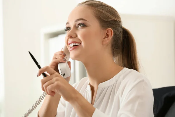 Beautiful female secretary talking on telephone in office — Stock Photo, Image