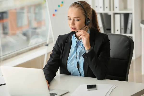 Hermosa secretaria hablando a través de auriculares en la oficina —  Fotos de Stock